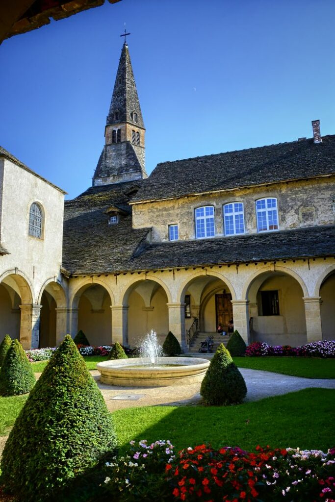 Scenic courtyard featuring a central fountain, arched walkways, and a historic tower.