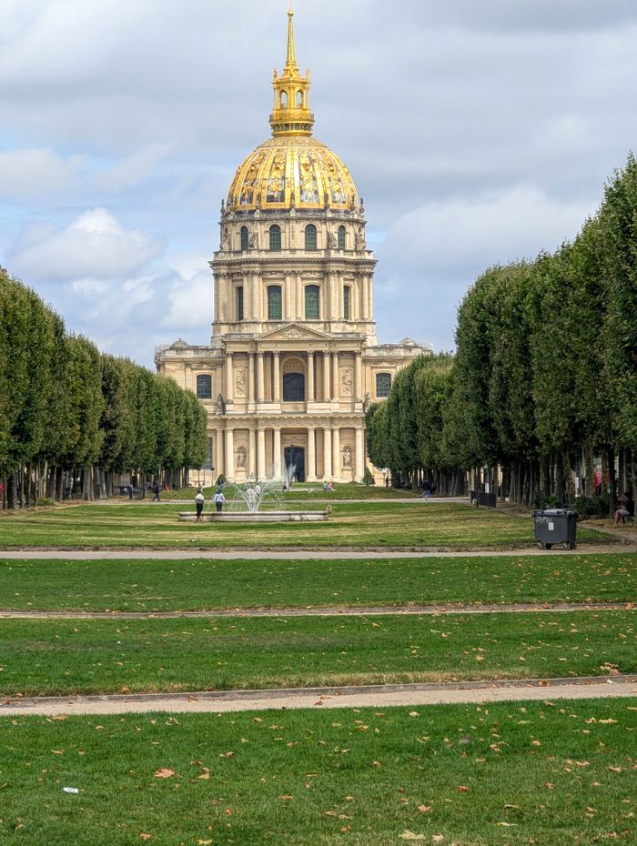 Les Invalides in Paris features a striking golden dome surrounded by lush gardens and vibrant greenery.