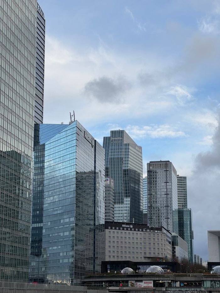 Stunning view of modern skyscrapers in La Défense district of Paris under a partly cloudy sky.