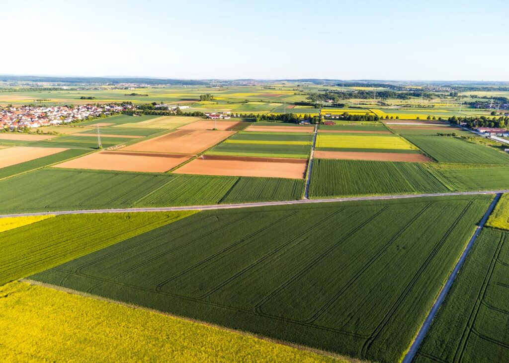 Stunning aerial view of vibrant patchwork agricultural fields and a distant village.